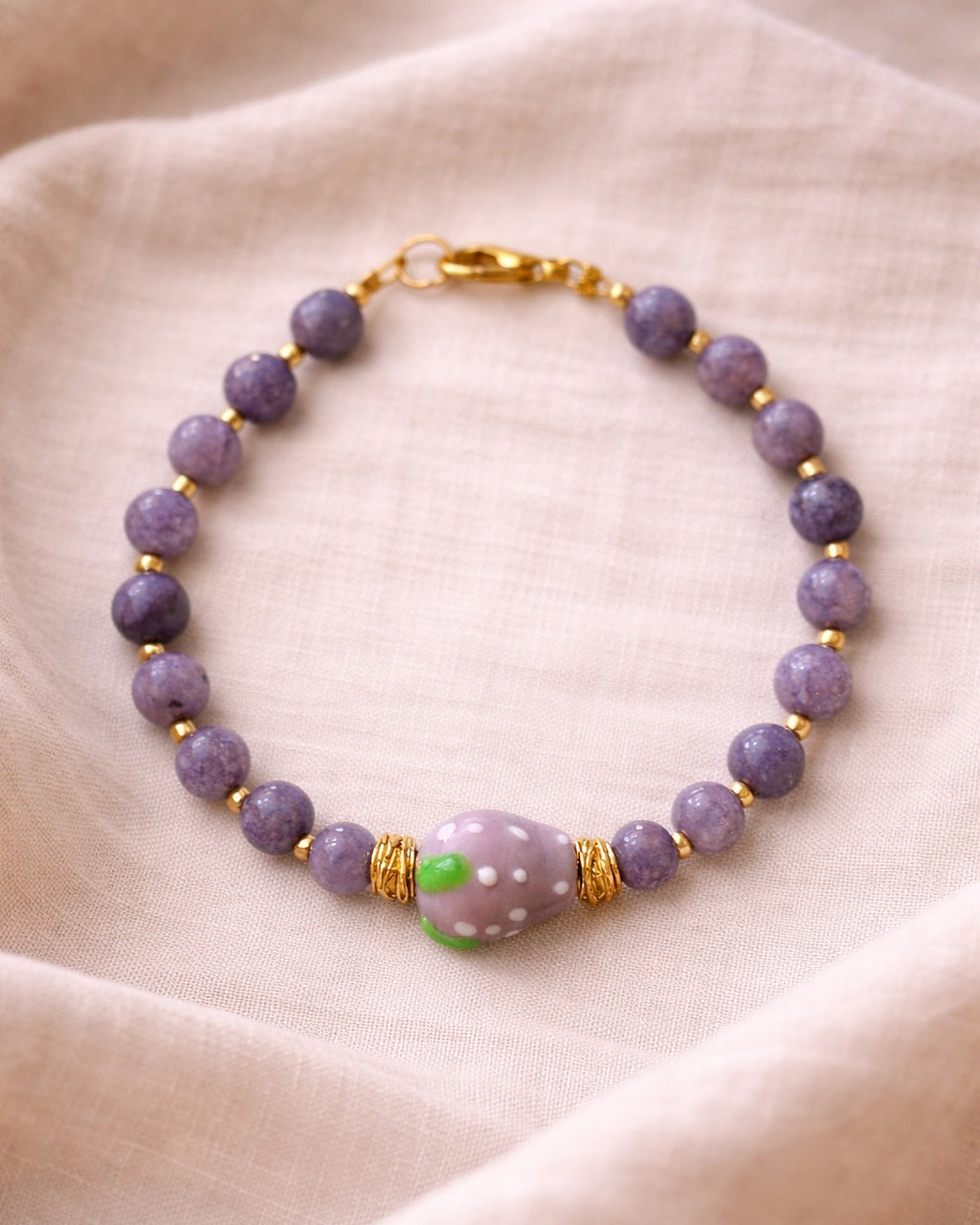Purple beaded bracelet with a ceramic strawberry charm