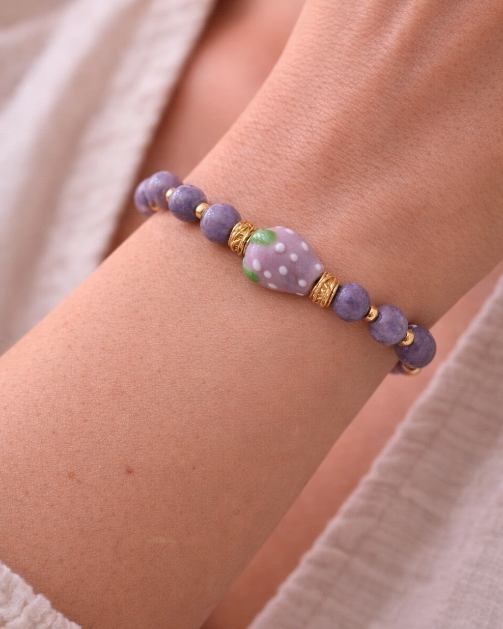 Purple beaded bracelet with a ceramic strawberry charm