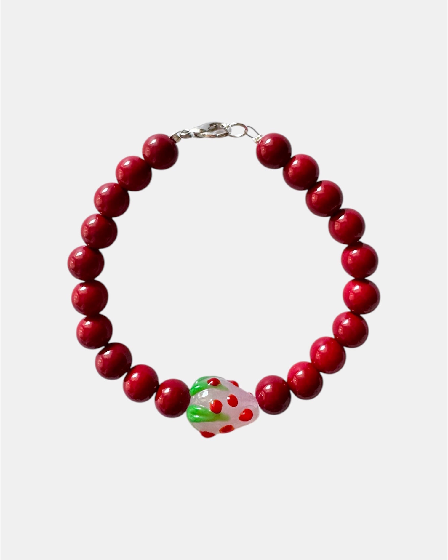 Red beaded bracelet featuring a playful strawberry charm for a fun and cute look