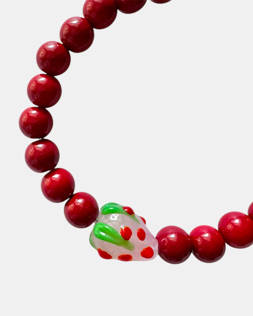 Red beaded bracelet featuring a playful strawberry charm for a fun and cute look