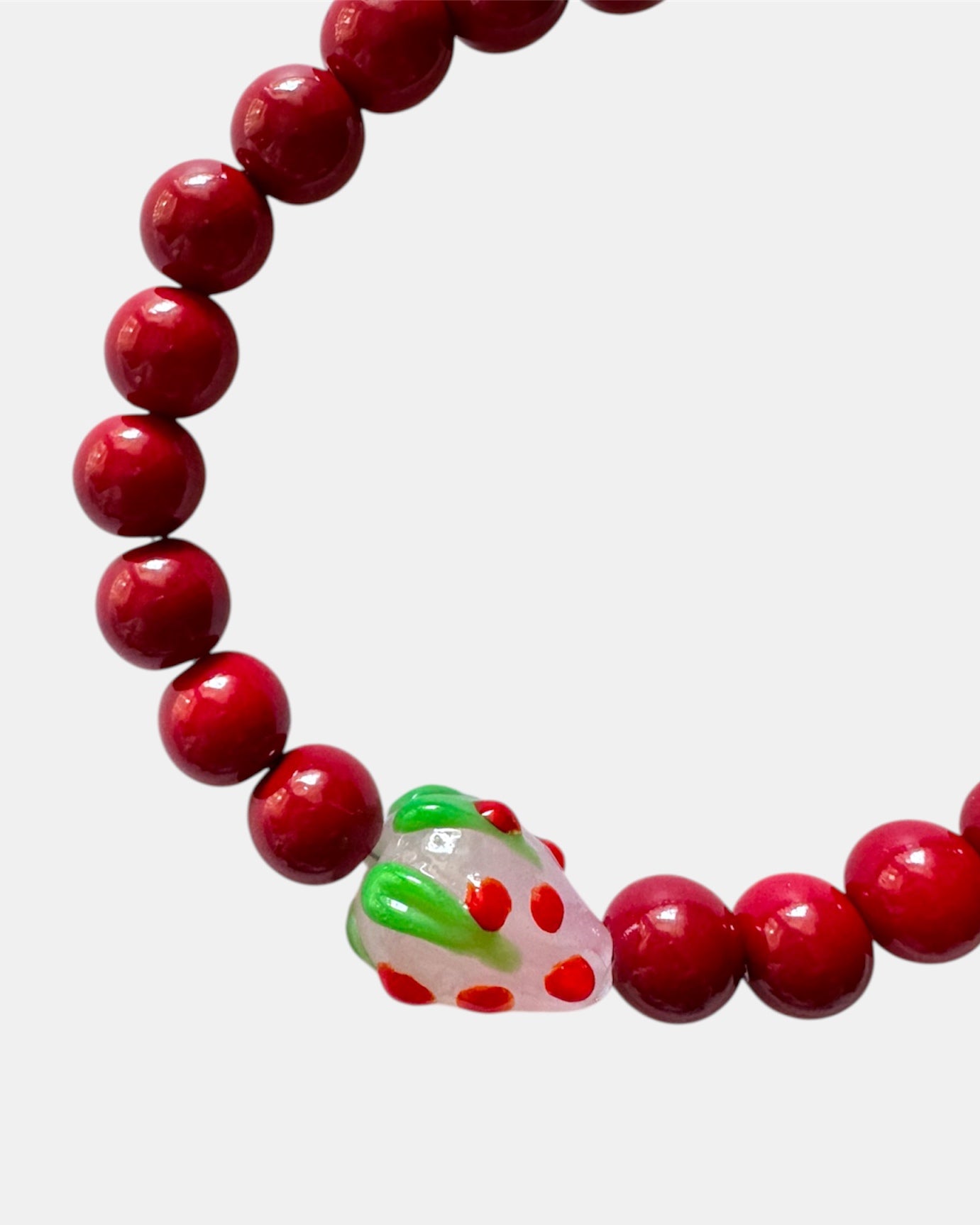 Red beaded bracelet featuring a playful strawberry charm for a fun and cute look