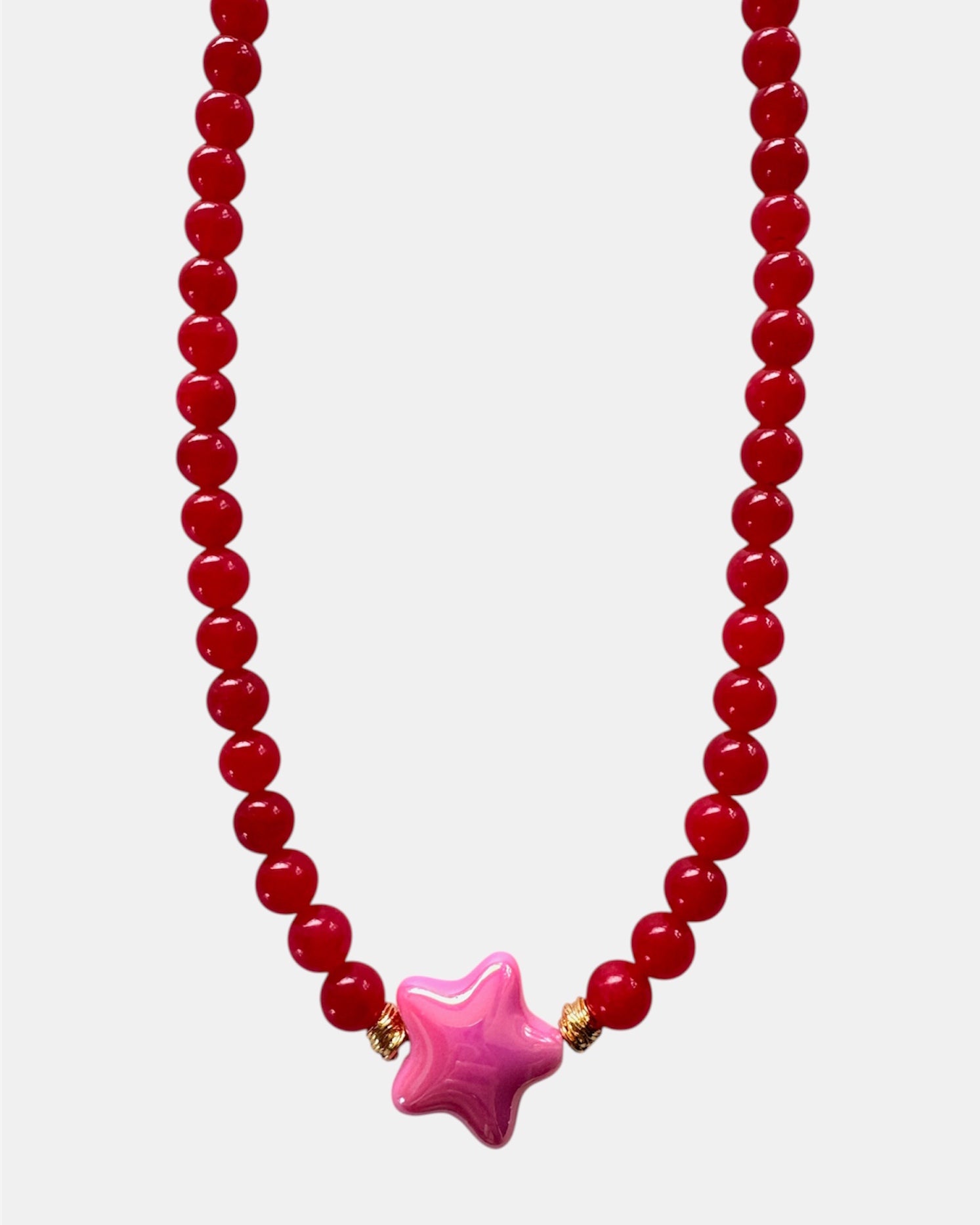 Beaded necklace with a pink star-shaped pendant on a white background