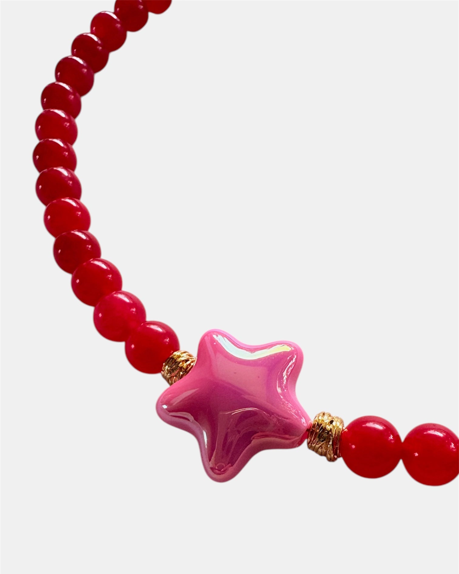Red beaded bracelet with a pink star-shaped charm on a white background