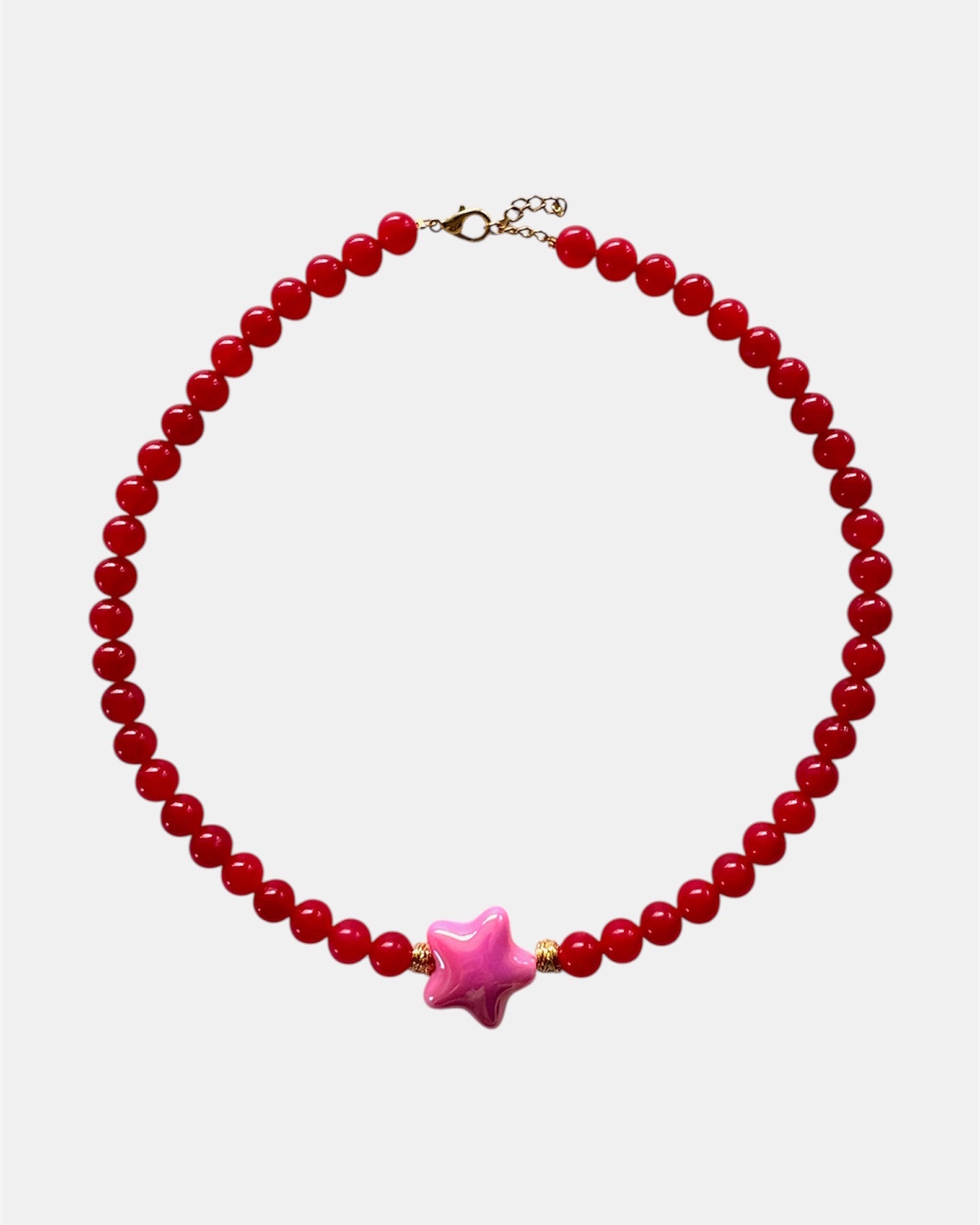 Necklace with red beads and a pink star-shaped charm on a white background