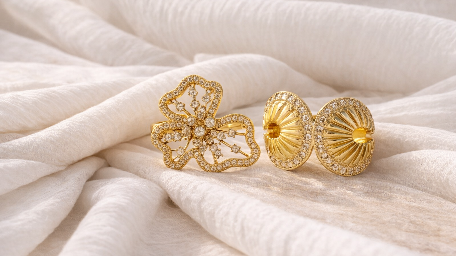 Two gold earrings on a textured white fabric background