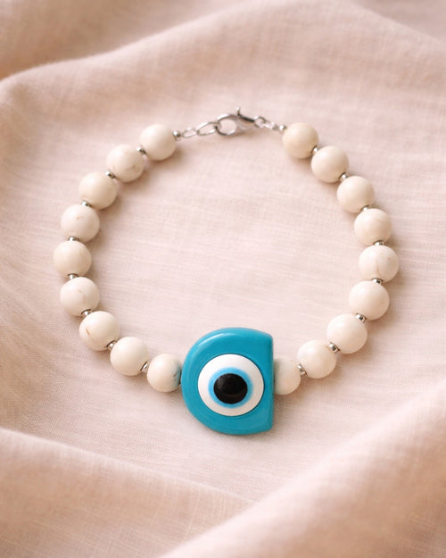 Silver bracelet with ecru beads and a turquoise evil eye charm
