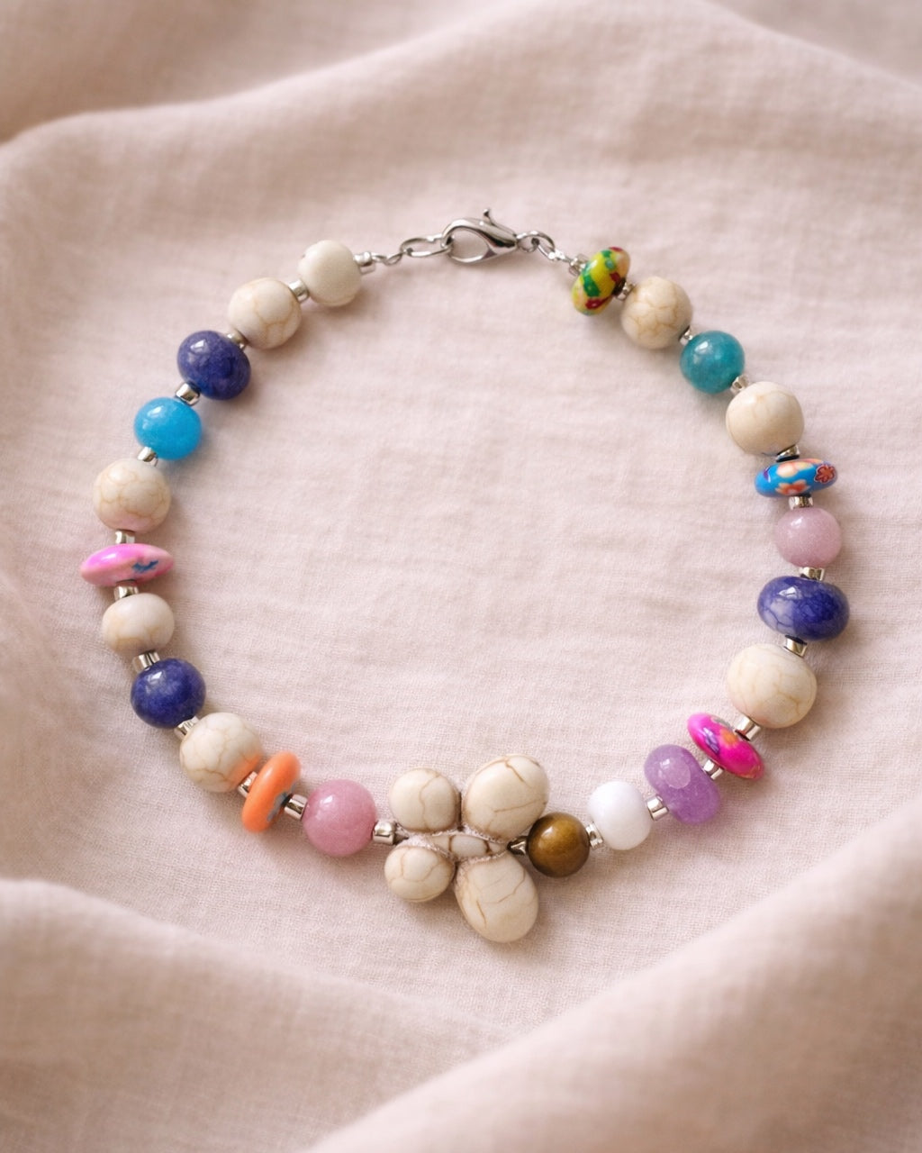 Silver bracelet with ecru and multicolored beads featuring a butterfly charm