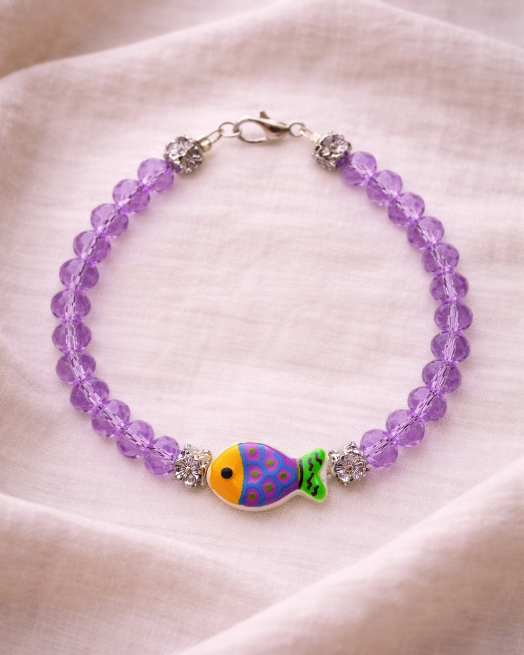 Elegant silver bracelet with purple crystal beads and fish charm, unique handmade jewelry inspired by the sea and modern style