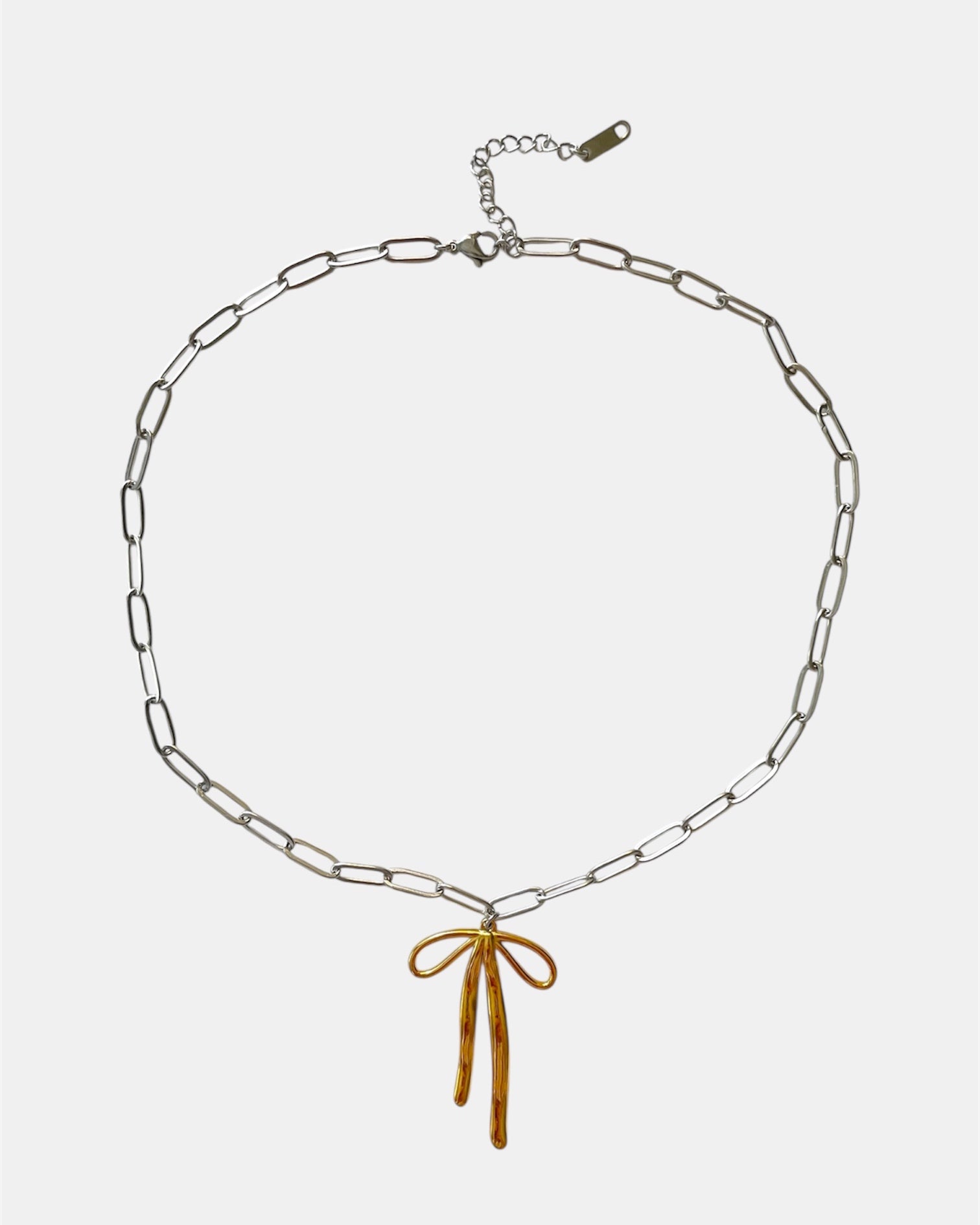 Silver chain necklace with a gold bow pendant