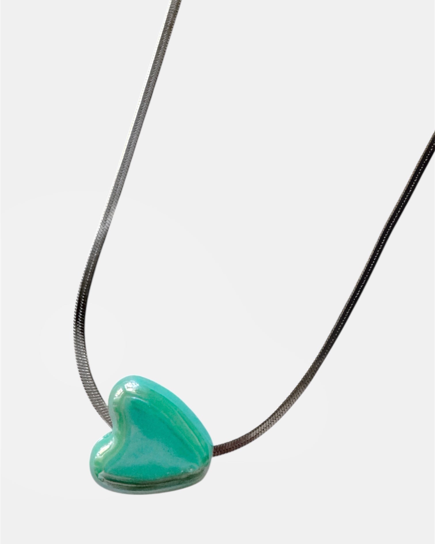 Silver chain necklace with a green heart charm