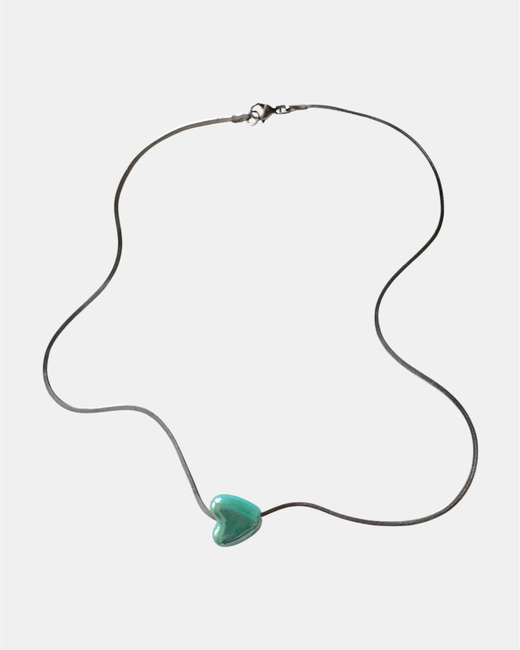 Silver chain necklace with a green heart charm