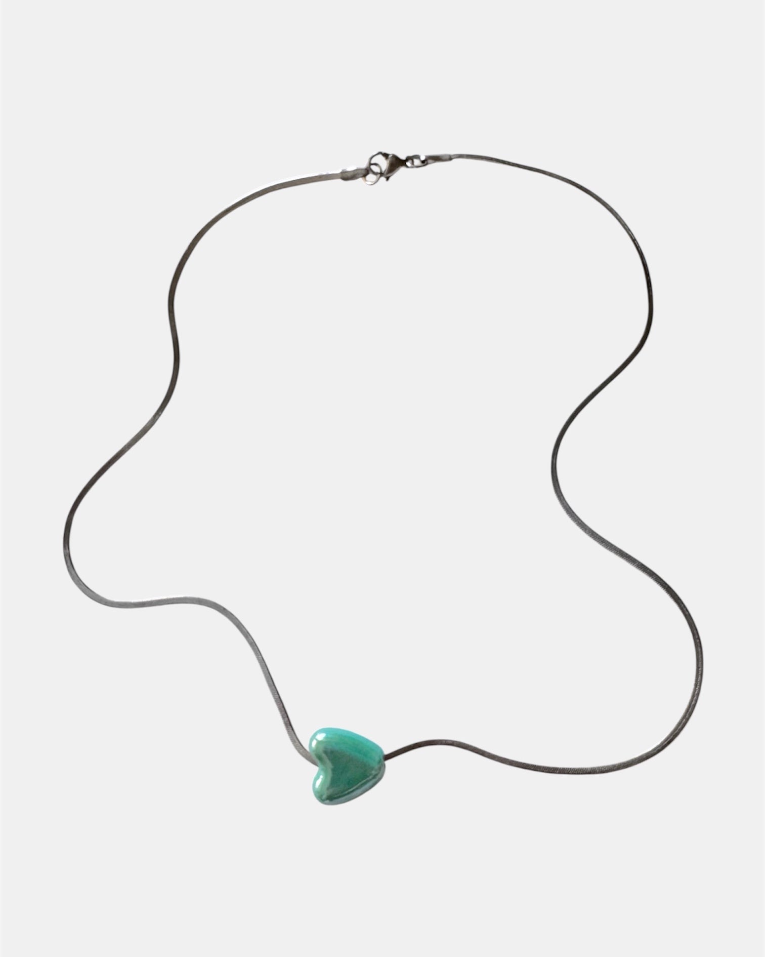 Silver chain necklace with a green heart charm