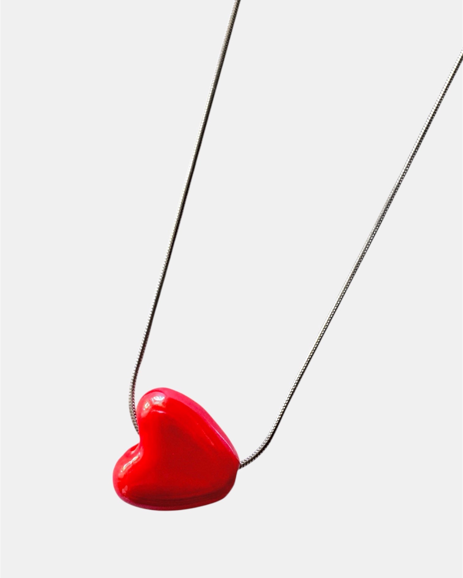 Silver chain necklace with a red heart charm