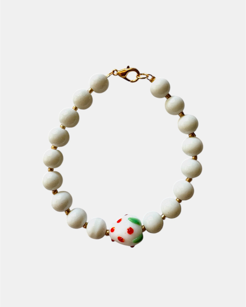 White beaded bracelet with a ceramic strawberry charm