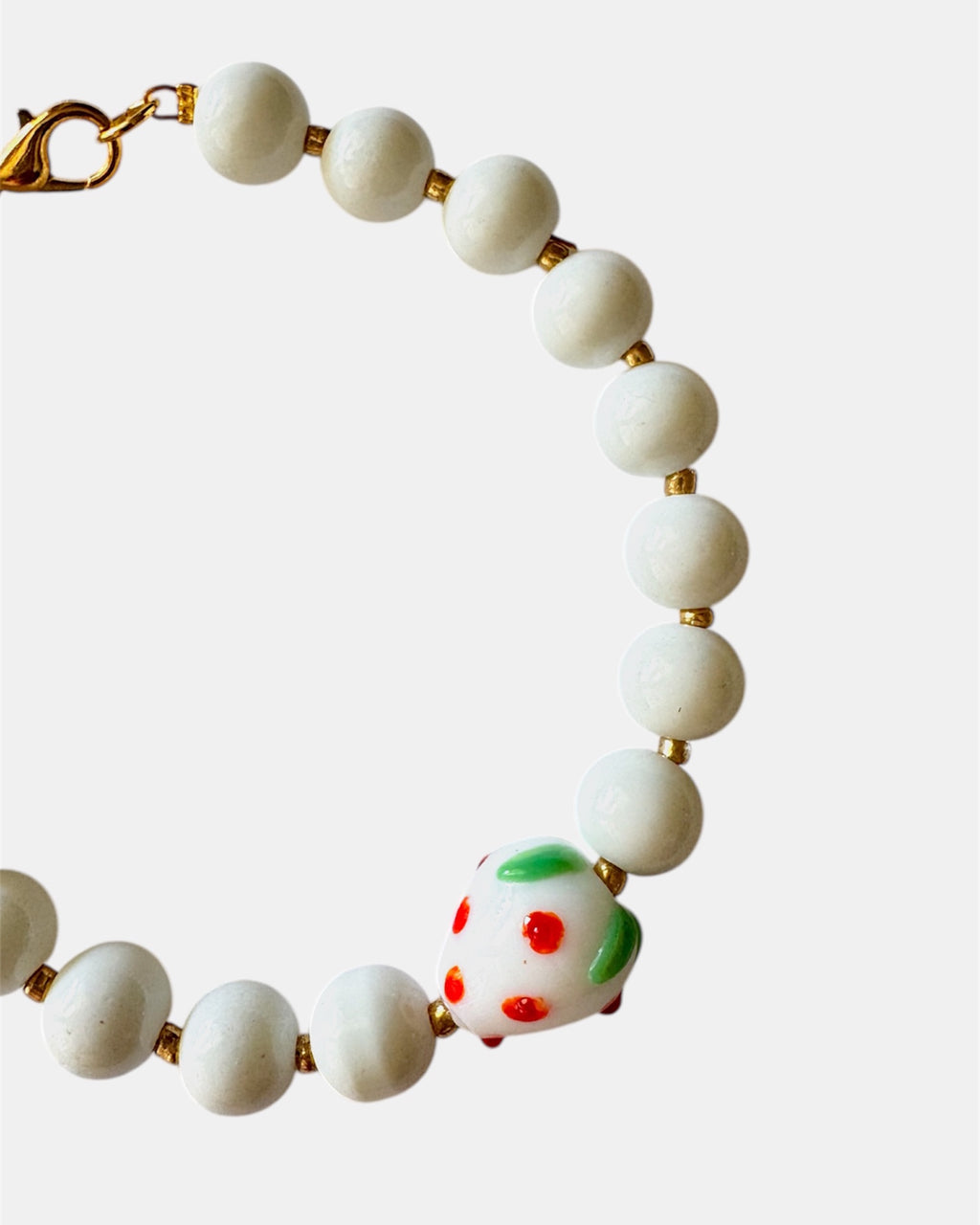 White beaded bracelet with a ceramic strawberry charm