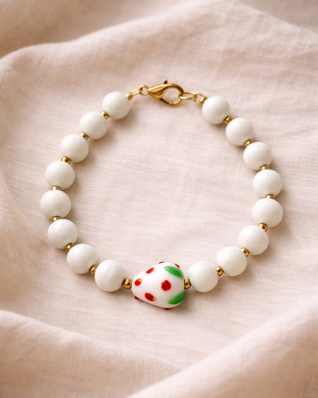 White beaded bracelet with a ceramic strawberry charm
