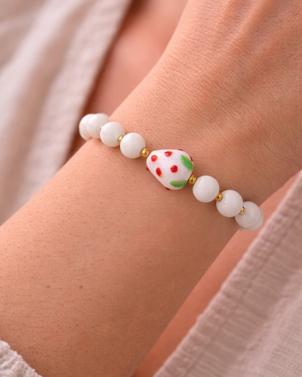 White beaded bracelet with a ceramic strawberry charm