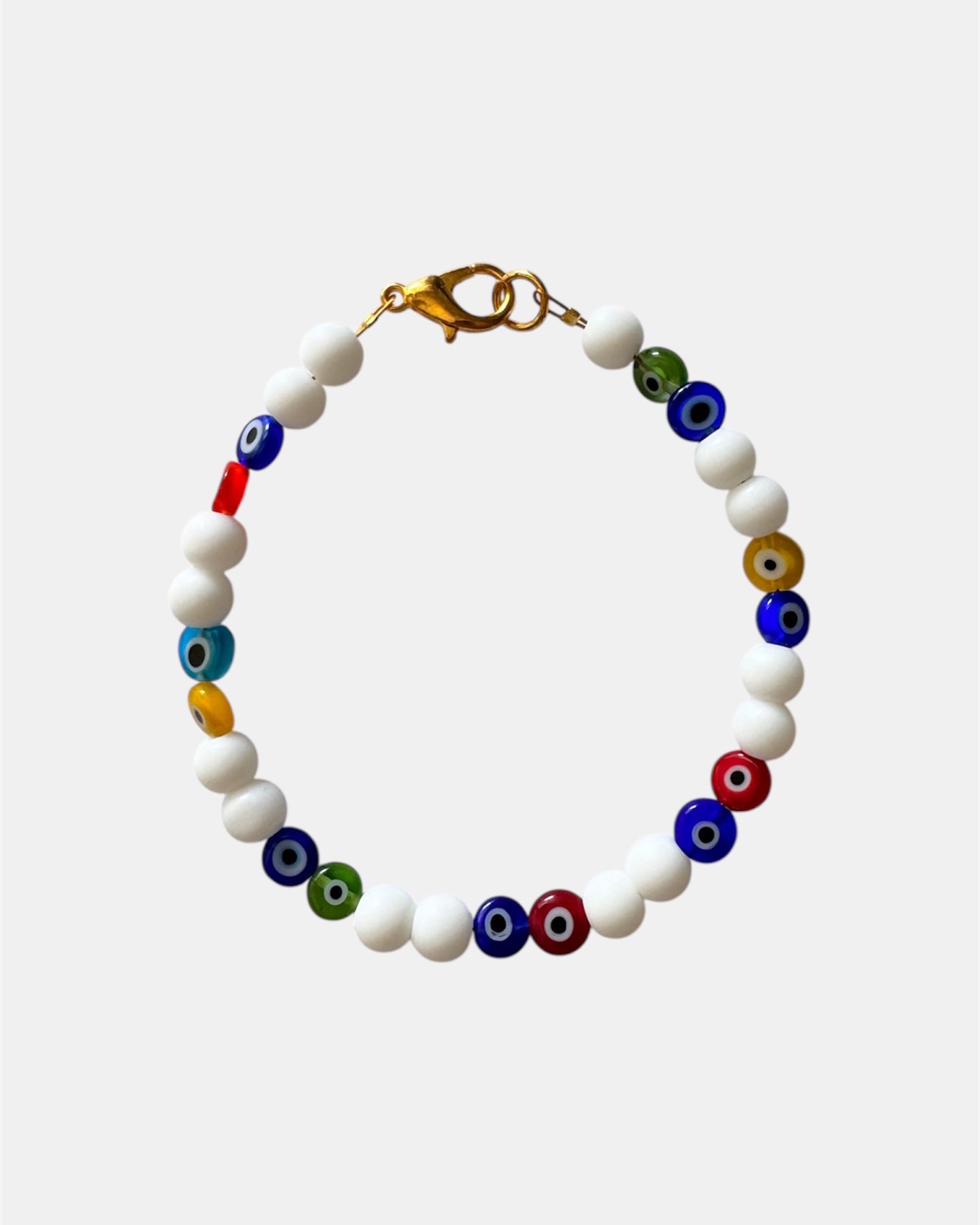 Bracelet with white beads and multicolored evil eye beads on a light gray background